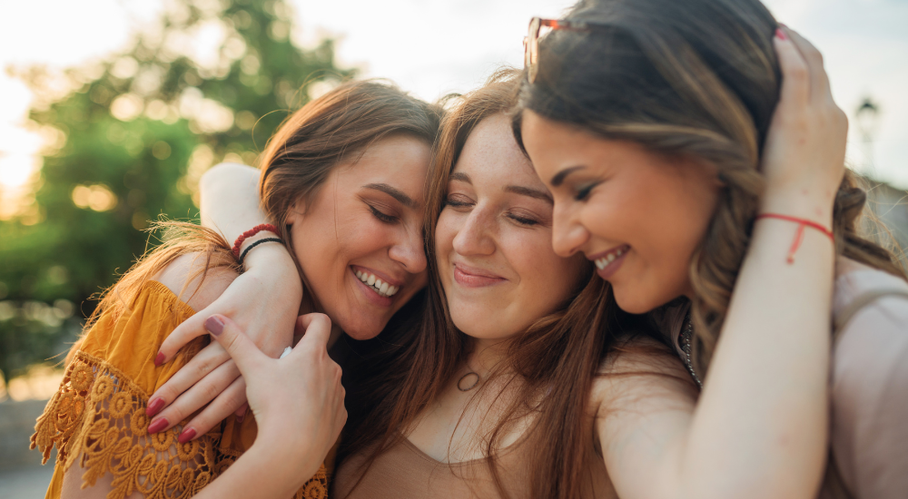 Drei Freundinnen sitzen zusammen und lachen – symbolisiert die Freude und das Verständnis in Freundschaften.