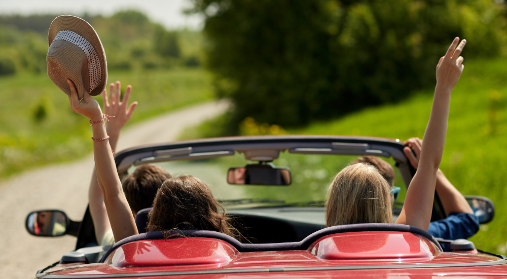 Vier Personen fahren in einem Auto und haben Spaß – symbolisiert die Freude am gemeinsamen Entdecken und Schenken.